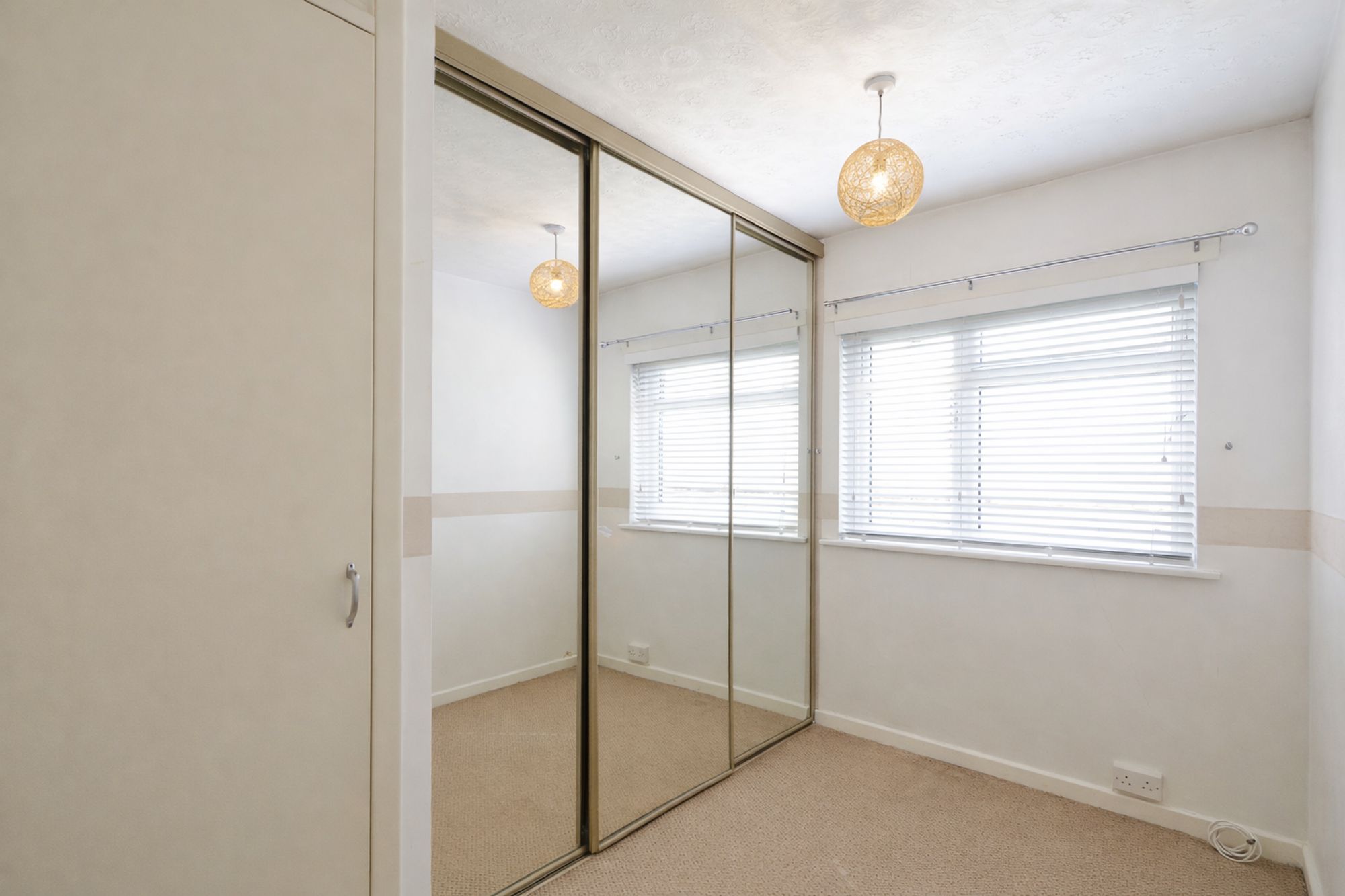 Sunny bedroom with mirrored wardrobe and blinds